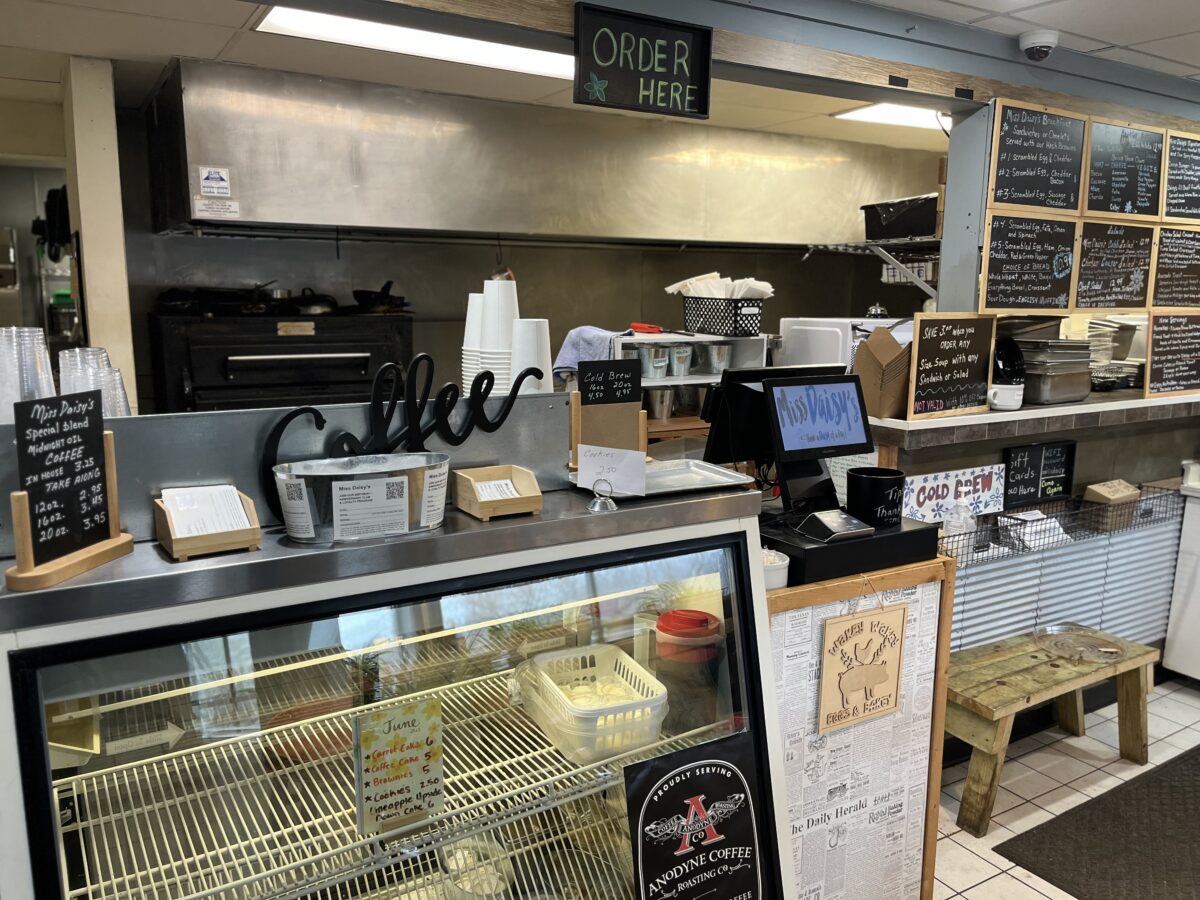 The coffee display case and order counter area with a refrigerated display and "Order Here" sign at Miss Daisy's.